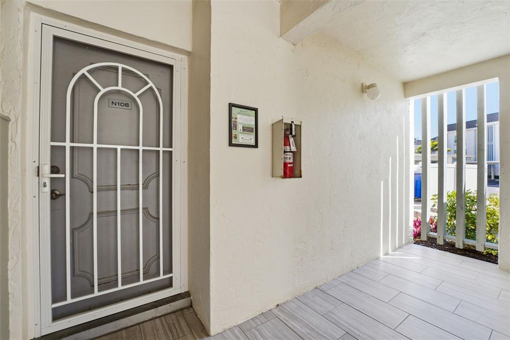 A white security door labeled N106 leads to a tiled entryway with a fire extinguisher — 4440 EXETER DRIVE UNIT 106, LONGBOAT KEY, FL