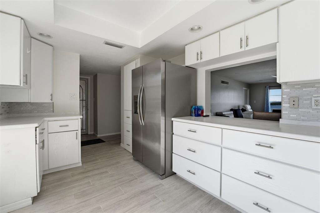 A kitchen features white cabinets, stainless steel appliances, and light-colored tile flooring — 4440 EXETER DRIVE UNIT 106, LONGBOAT KEY, FL