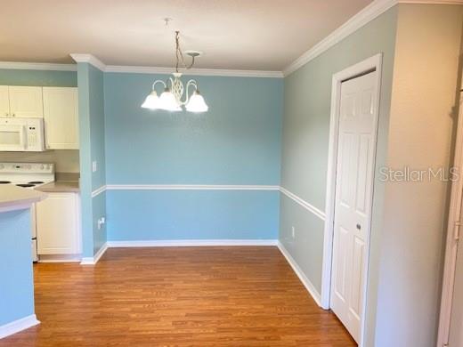 A dining area features light blue walls, a white chandelier, and hardwood flooring — 4201 WOODSTORKS WALK WAY UNIT 3111, LUTZ, FL