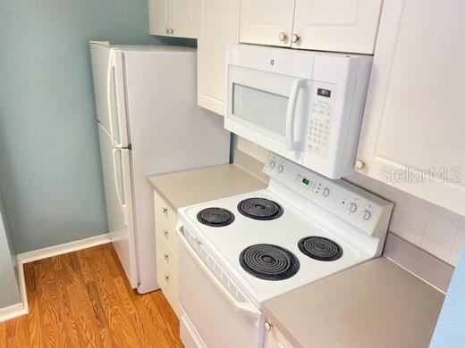A kitchen features white appliances, light-colored cabinets, and wood-look flooring — 4201 WOODSTORKS WALK WAY UNIT 3111, LUTZ, FL