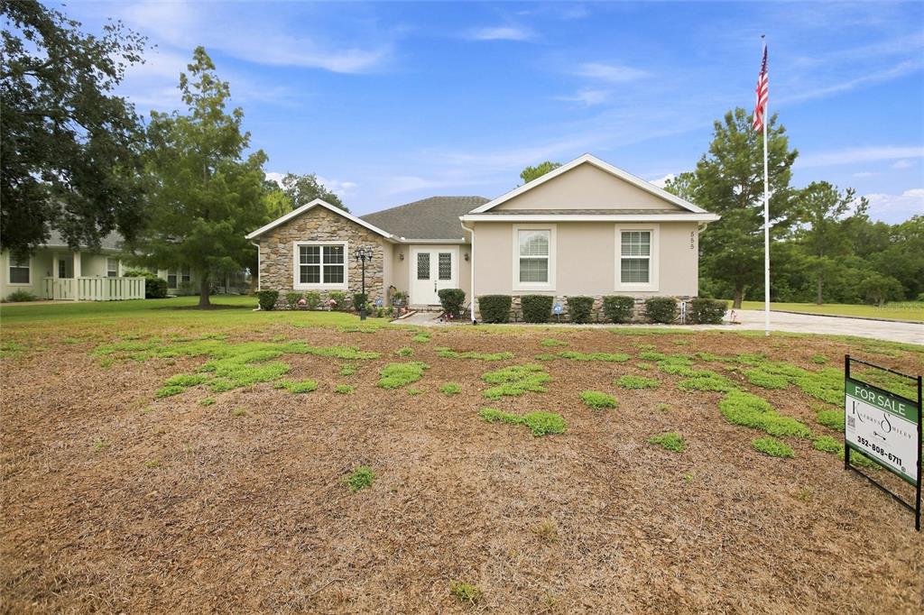 A single-story house with a paved driveway and a flag pole in the front yard — 555 DOWLING CIRCLE, LADY LAKE, FL