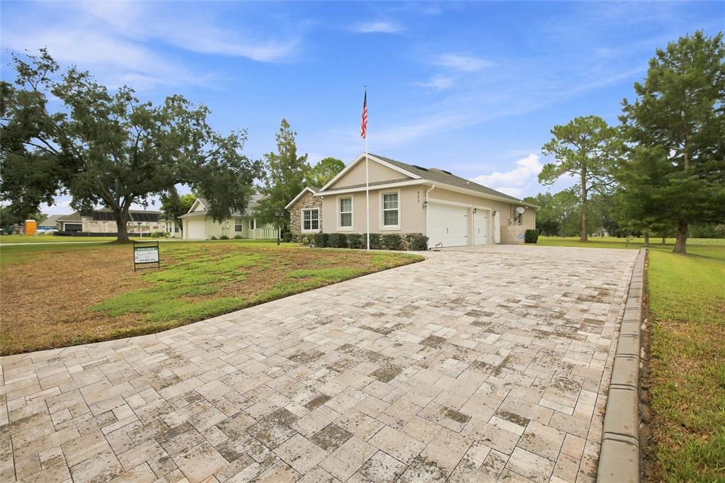 A stone-accented house exterior features a paved walkway leading to a white double front door — 555 DOWLING CIRCLE, LADY LAKE, FL
