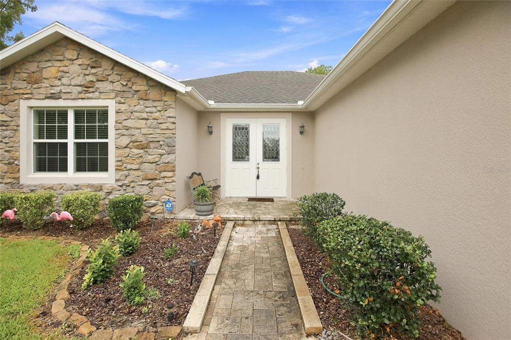 The rear exterior of a single-story house features a screened-in lanai and a grassy yard — 555 DOWLING CIRCLE, LADY LAKE, FL
