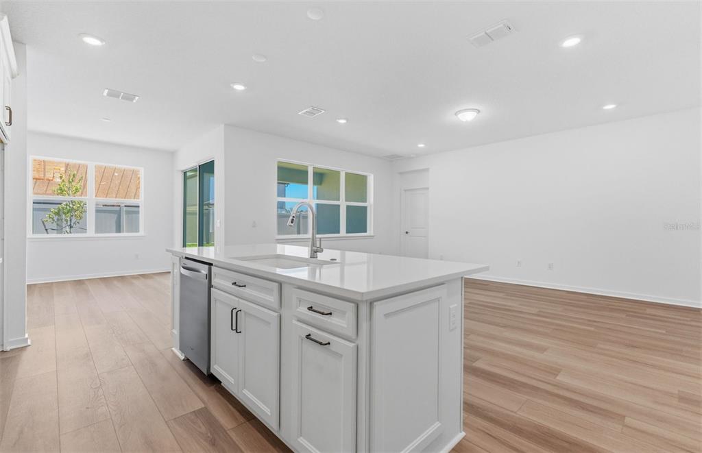 A kitchen island with a stainless steel dishwasher sits in a room with white walls — 6979 DEPUE DRIVE, WESLEY CHAPEL, FL