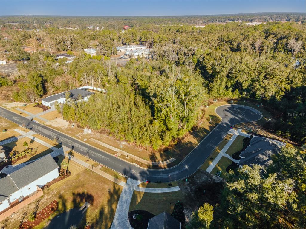 An aerial view shows a vacant, wooded residential lot situated on a curved suburban street — 684 SW 139TH COURT, NEWBERRY, FL