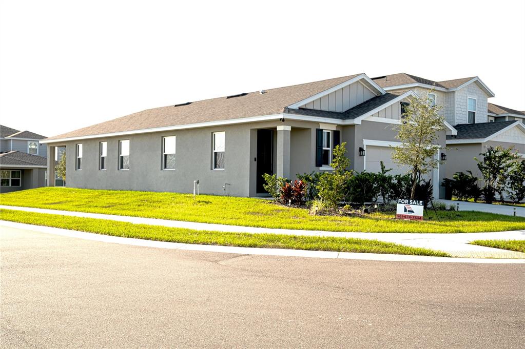 A single-story suburban house with a gray stucco exterior and a for sale sign — 5503 BLUEBONNET PLACE, HAINES CITY, FL