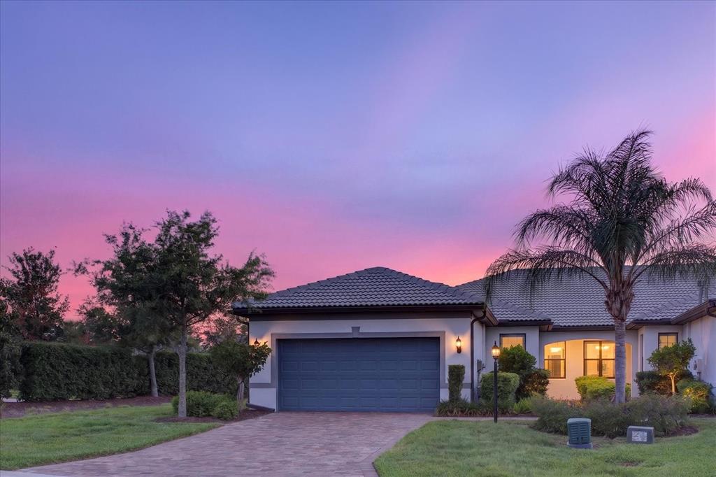 A single-story house with a two-car garage and a palm tree at sunset — 17658 CAMDEN DRIVE, BRADENTON, FL