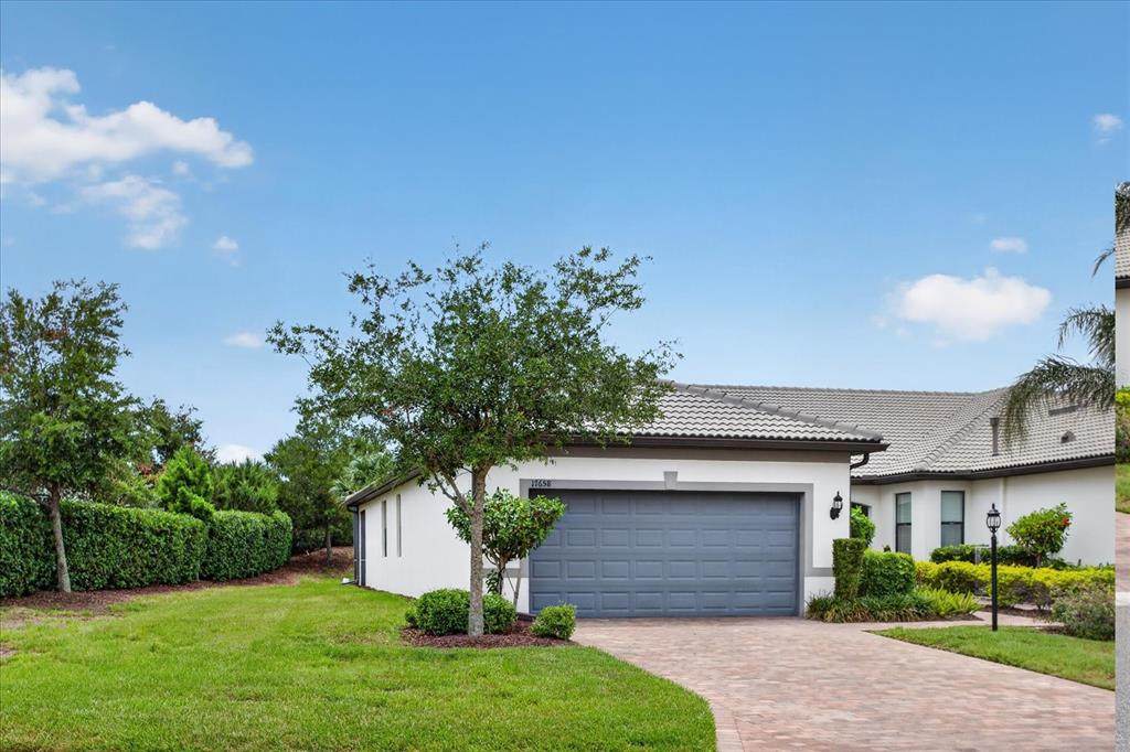 A single-story house with a gray garage door, a paved driveway, and a grassy lawn — 17658 CAMDEN DRIVE, BRADENTON, FL