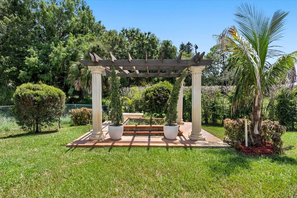A backyard features a swimming pool, palm trees, and a house with a tiled roof — 1819 SE ELROSE STREET, PORT ST LUCIE, FL