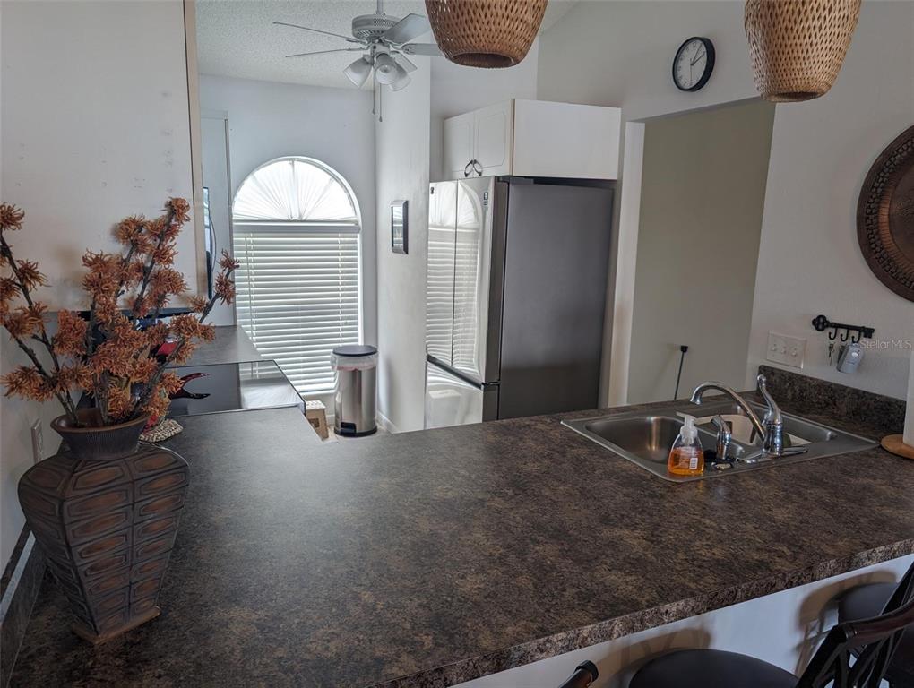 A kitchen features dark laminate countertops, a stainless steel refrigerator, and a large arched window — 308 STEPHEN DRIVE UNIT 8, LAKE PLACID, FL