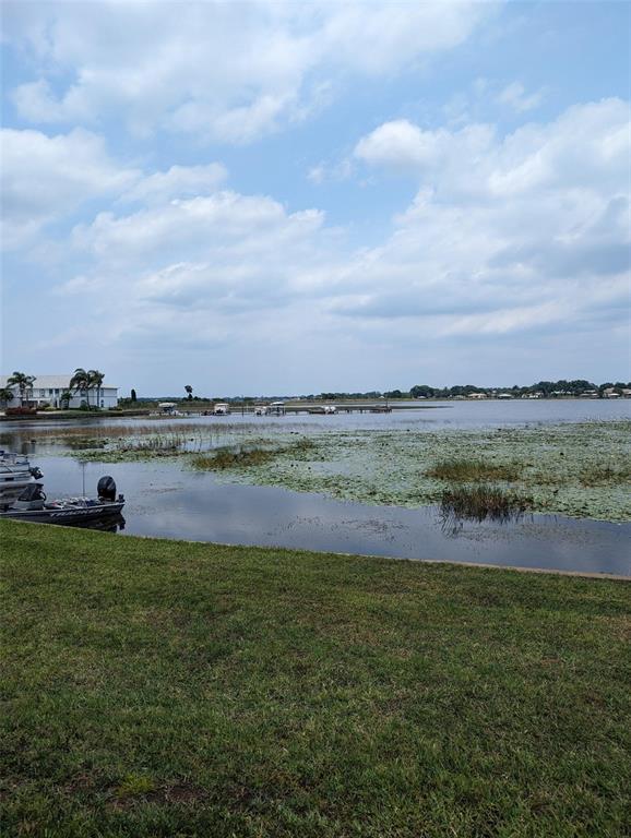 A grassy lawn overlooks a lake with lily pads and several docked boats — 308 STEPHEN DRIVE UNIT 8, LAKE PLACID, FL