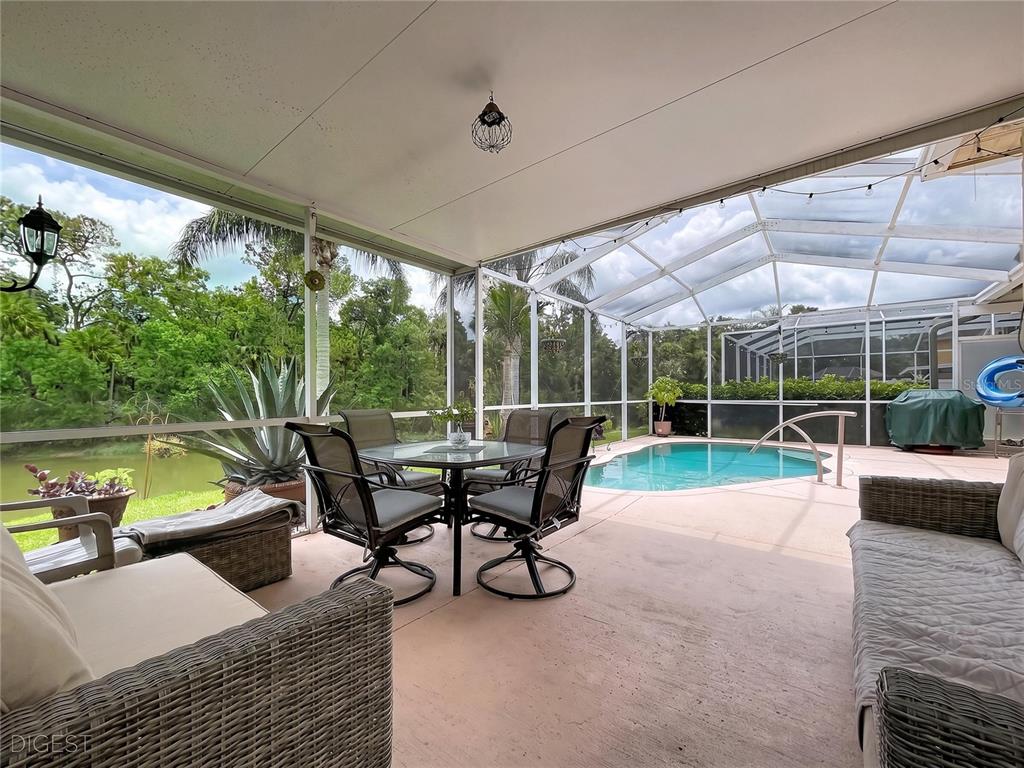 A covered patio features a dining set, lounge furniture, and an enclosed swimming pool — 27544 BREAKERS DRIVE, WESLEY CHAPEL, FL