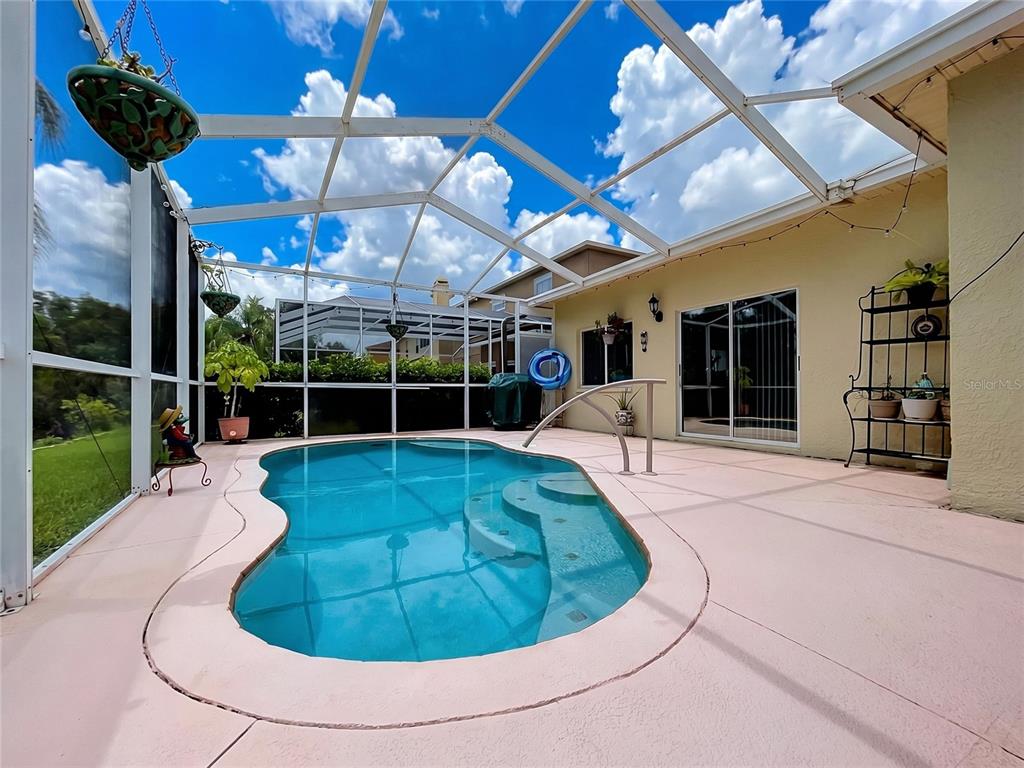 A screened-in patio features a swimming pool with steps and a light-colored concrete deck — 27544 BREAKERS DRIVE, WESLEY CHAPEL, FL