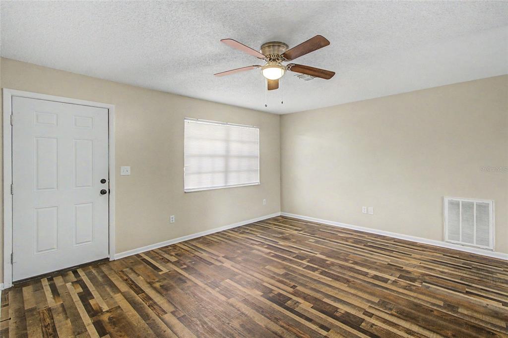 A living room features a sectional sofa, a large area rug, and tall wooden bookshelves — 1733 LARKIN ROAD, SPRING HILL, FL