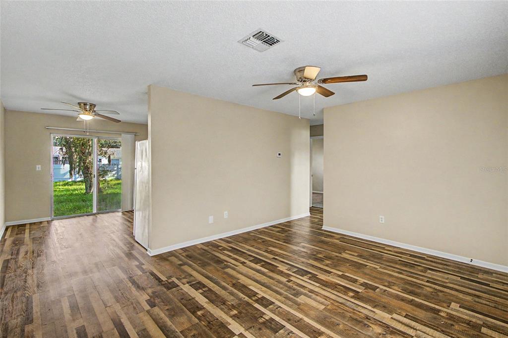 A bedroom features a bed, a wall-mounted television, a dresser, and a doorway to a bathroom — 1733 LARKIN ROAD, SPRING HILL, FL