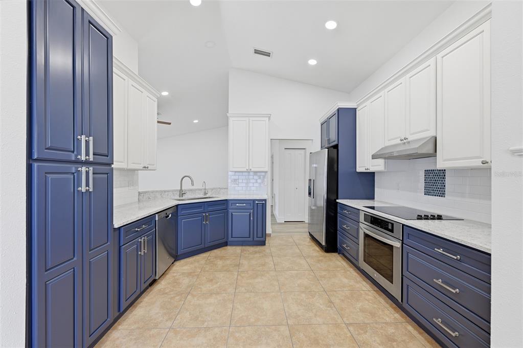 A kitchen with blue lower cabinets, white upper cabinets, stainless steel appliances, and tile flooring — 1307 FLAXWOOD AVENUE, BRANDON, FL