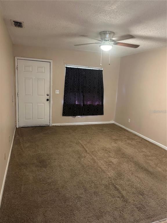 A room with brown carpet, a ceiling fan, a white door, and a window with curtains — 8203 N KLONDYKE STREET UNIT B, TAMPA, FL