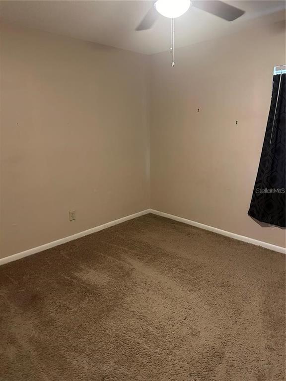 An empty bedroom features beige walls, brown carpeting, a ceiling fan, and a window with curtains — 8203 N KLONDYKE STREET UNIT B, TAMPA, FL