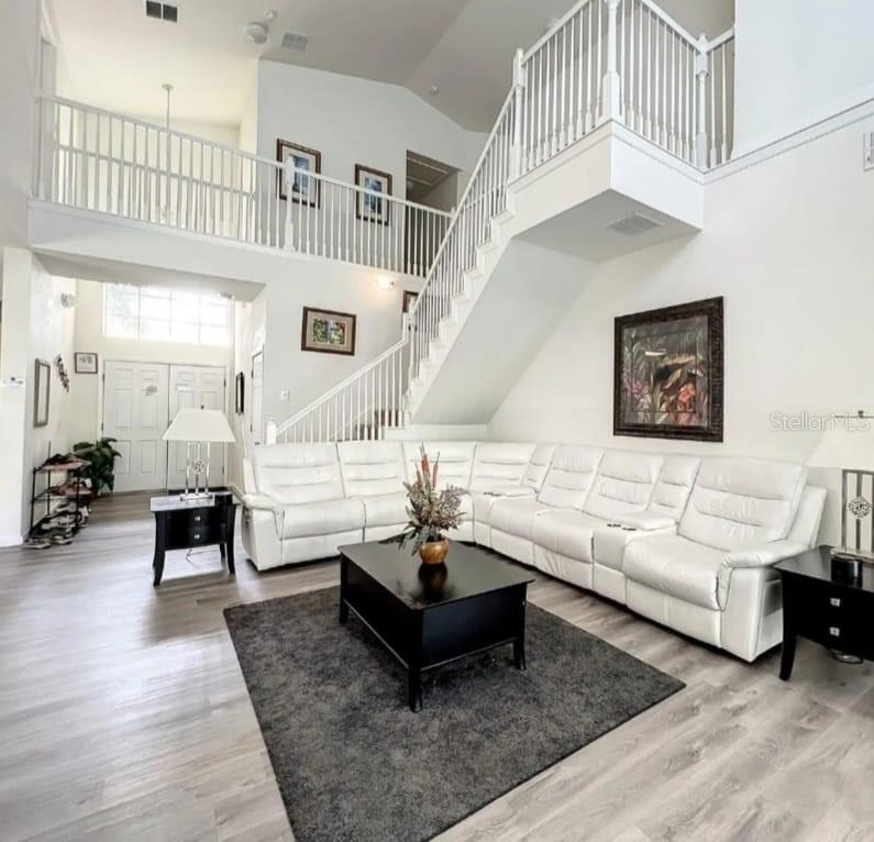 A living room with a white sectional sofa, dark coffee table, and a staircase — 143 E WINDSOR PLACE, DAVENPORT, FL