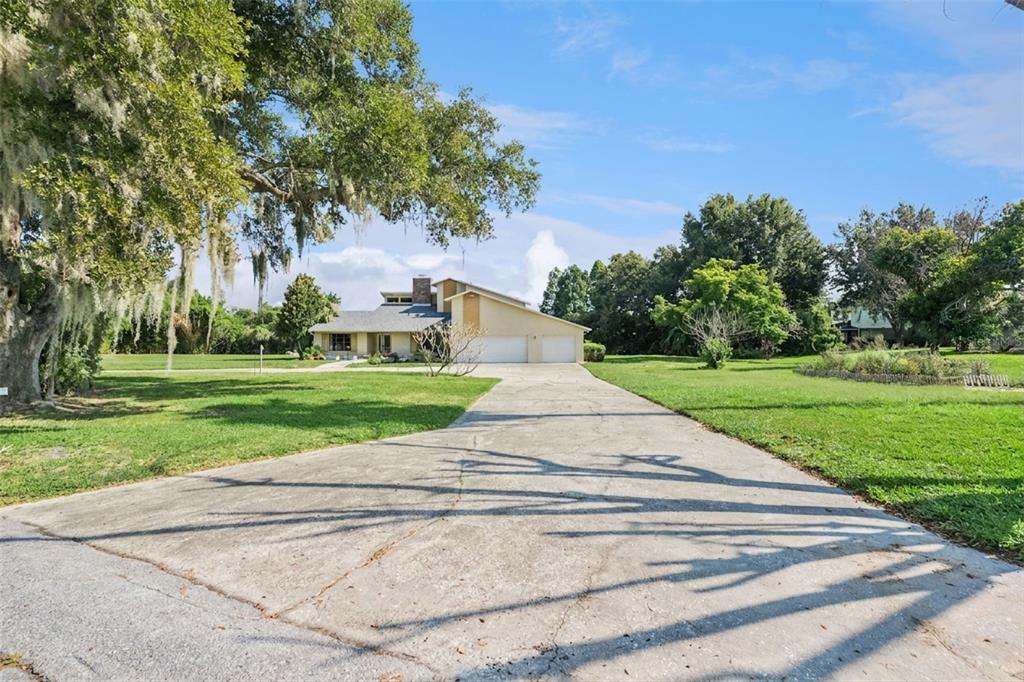 An aerial view shows a house with a screened-in pool and a large grassy yard — 25 LAKEWOOD CAUSEWAY, WINTER HAVEN, FL