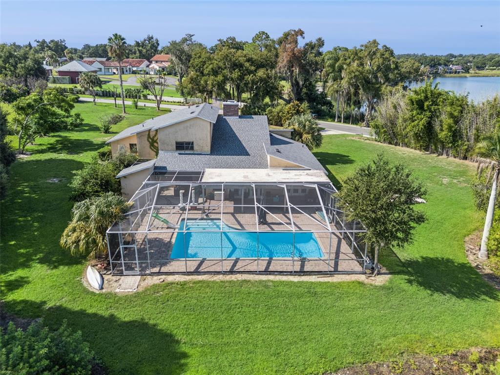 A long concrete driveway leads to a tan house with a two-car garage and trees — 25 LAKEWOOD CAUSEWAY, WINTER HAVEN, FL
