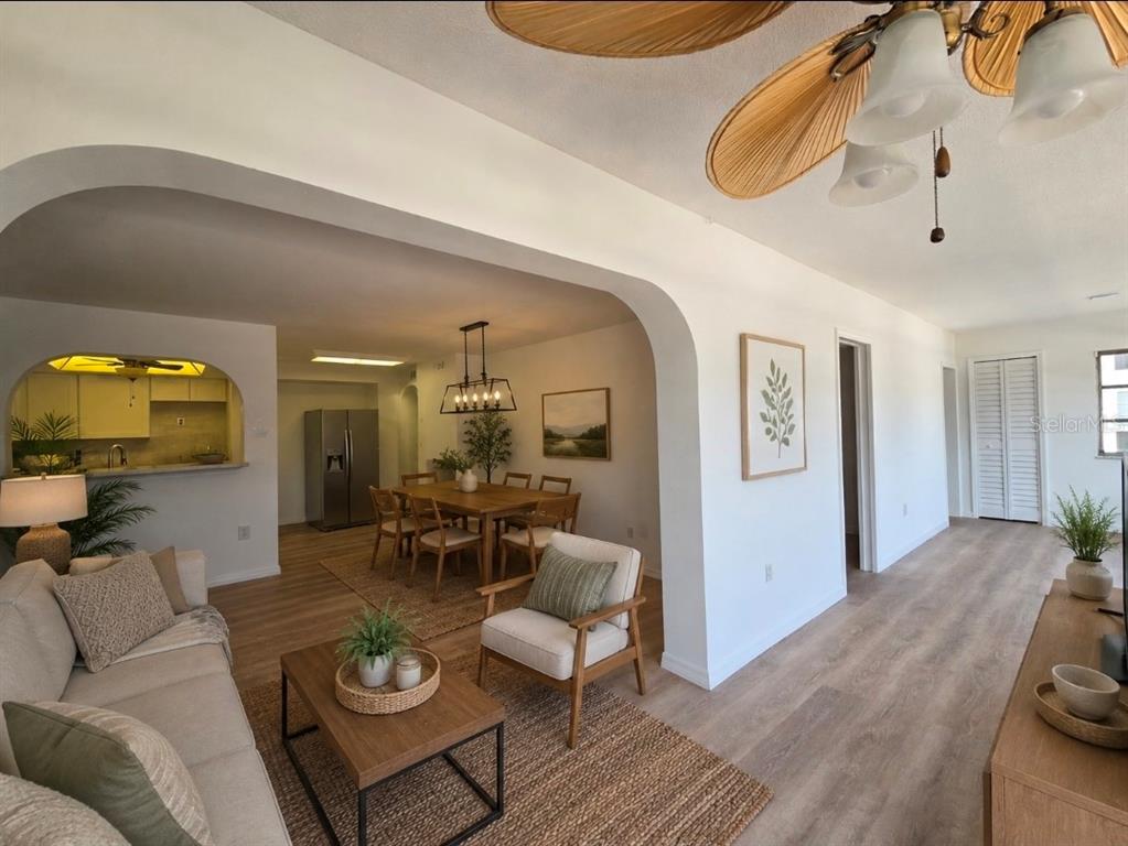 A living room with light wood flooring flows into a dining area and kitchen — 4812 JASPER DRIVE UNIT 101, NEW PORT RICHEY, FL