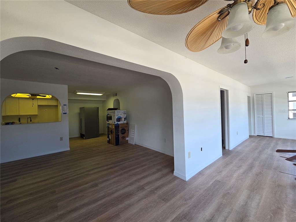 An interior view shows a living area with wood-look flooring leading to an open kitchen — 4812 JASPER DRIVE UNIT 101, NEW PORT RICHEY, FL