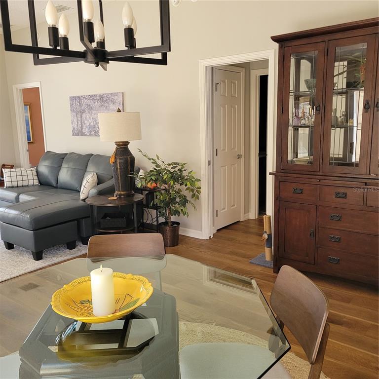 A dining area with a glass table and hutch opens into a living room with sofa — 1521 TRENTON LANE, THE VILLAGES, FL