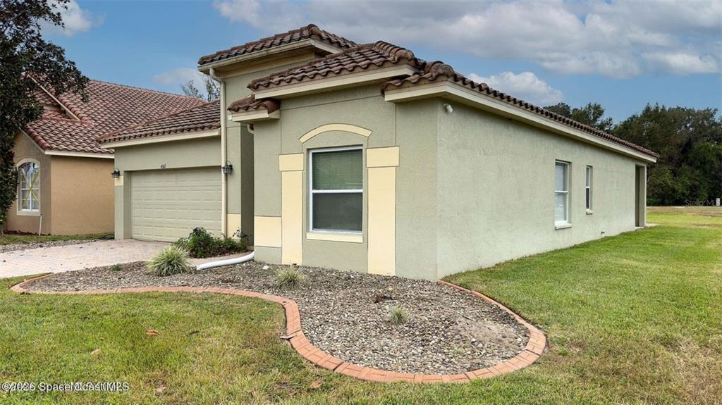 A single-story house with a tan stucco exterior, a tiled roof, and a two-car garage — 4367 FITZROY REEF DRIVE, MIMS, FL