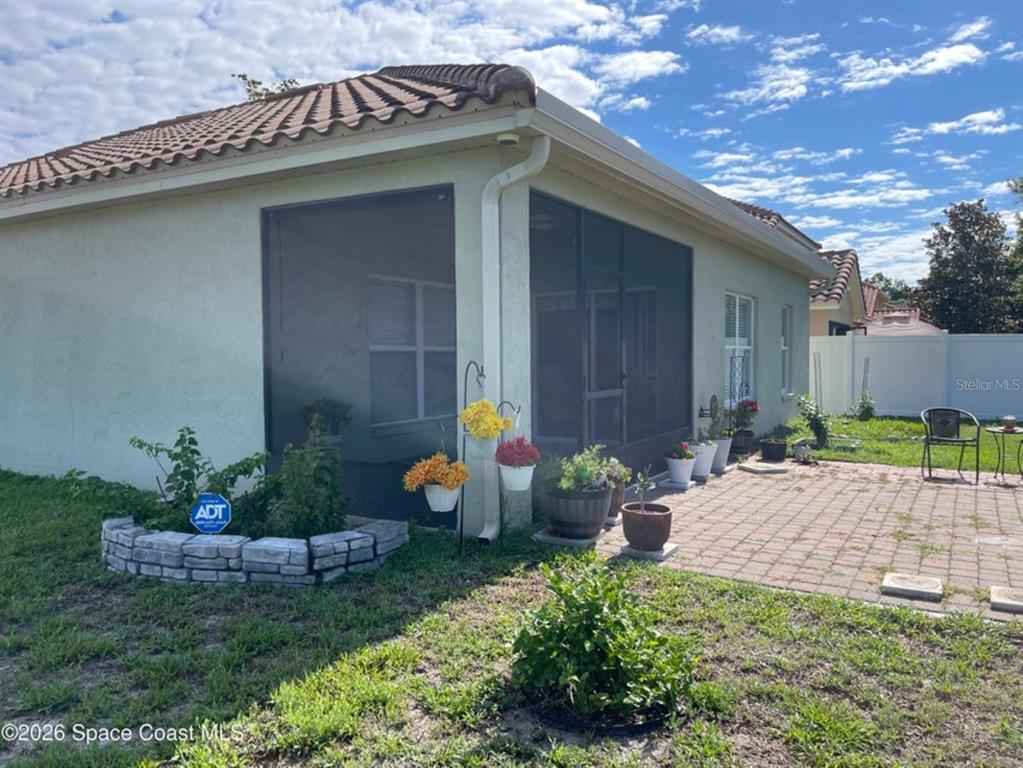 The exterior of a house features a screened-in patio, a brick paver area, and landscaping — 4367 FITZROY REEF DRIVE, MIMS, FL