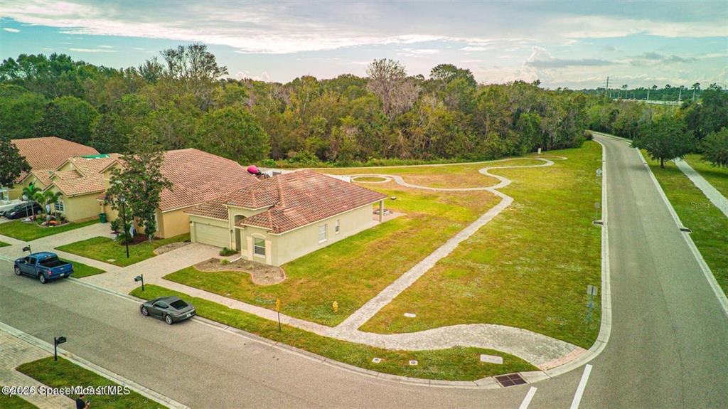 An aerial view shows a suburban house with a large, empty corner lot and sidewalk — 4367 FITZROY REEF DRIVE, MIMS, FL