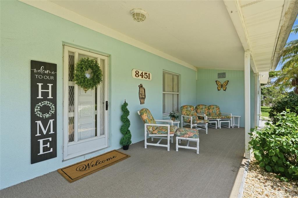 A covered front porch features light blue walls, a white door with a wreath, and furniture — 8451 SW SUNNYBREEZE ROAD, ARCADIA, FL