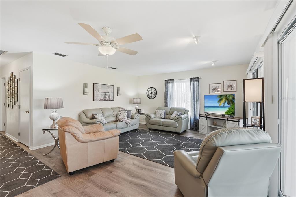 A living room features light-colored sofas, a dark geometric rug, and a ceiling fan — 8451 SW SUNNYBREEZE ROAD, ARCADIA, FL