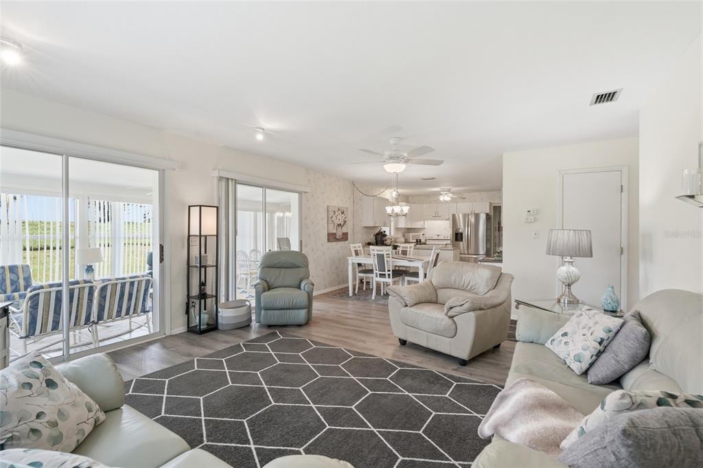 A living room with a geometric rug, light-colored furniture, and an open kitchen in the background — 8451 SW SUNNYBREEZE ROAD, ARCADIA, FL