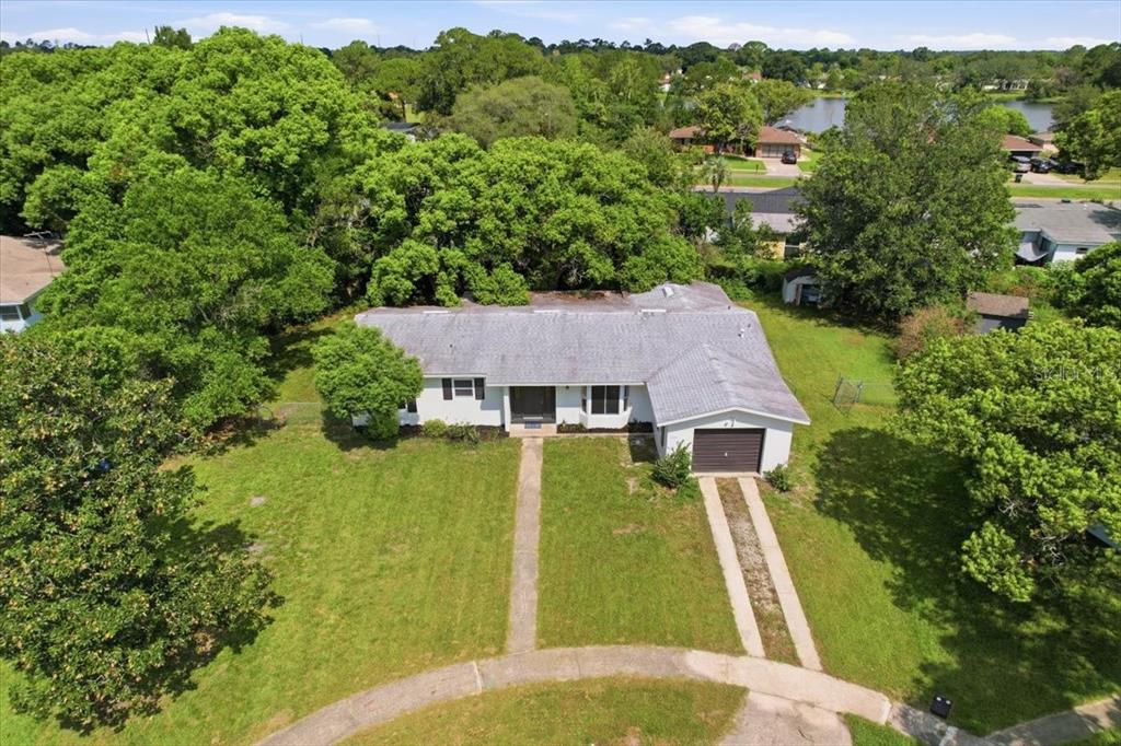 An aerial view shows a residential neighborhood with houses, driveways, and mature trees — 1220 SIENNA COURT, DELTONA, FL