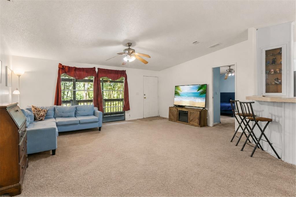 A living room features a blue sectional sofa, a television on a stand, and bar seating — 3002 SW 127TH AVENUE, WEBSTER, FL