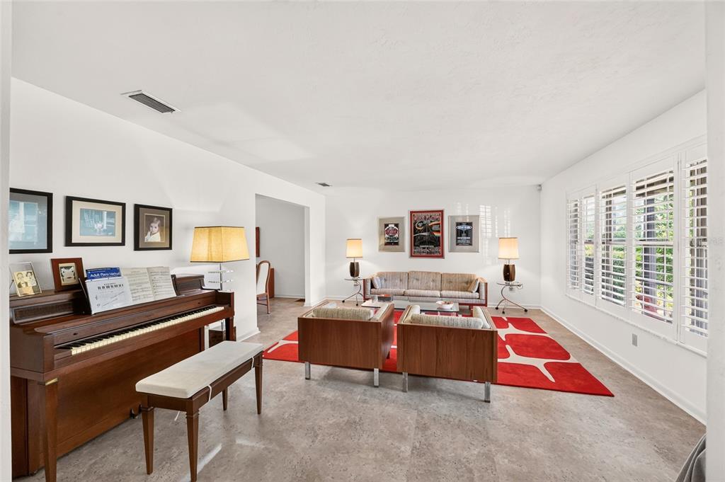A living room features a piano, mid-century modern furniture, a red area rug, and tile flooring — 4624 NW 19TH PLACE, GAINESVILLE, FL