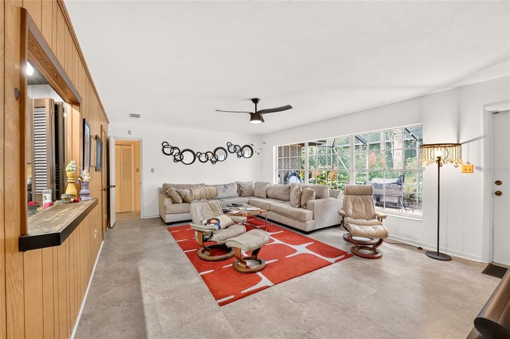 A living room features a beige sectional, two recliners, a red area rug, and wood paneling — 4624 NW 19TH PLACE, GAINESVILLE, FL