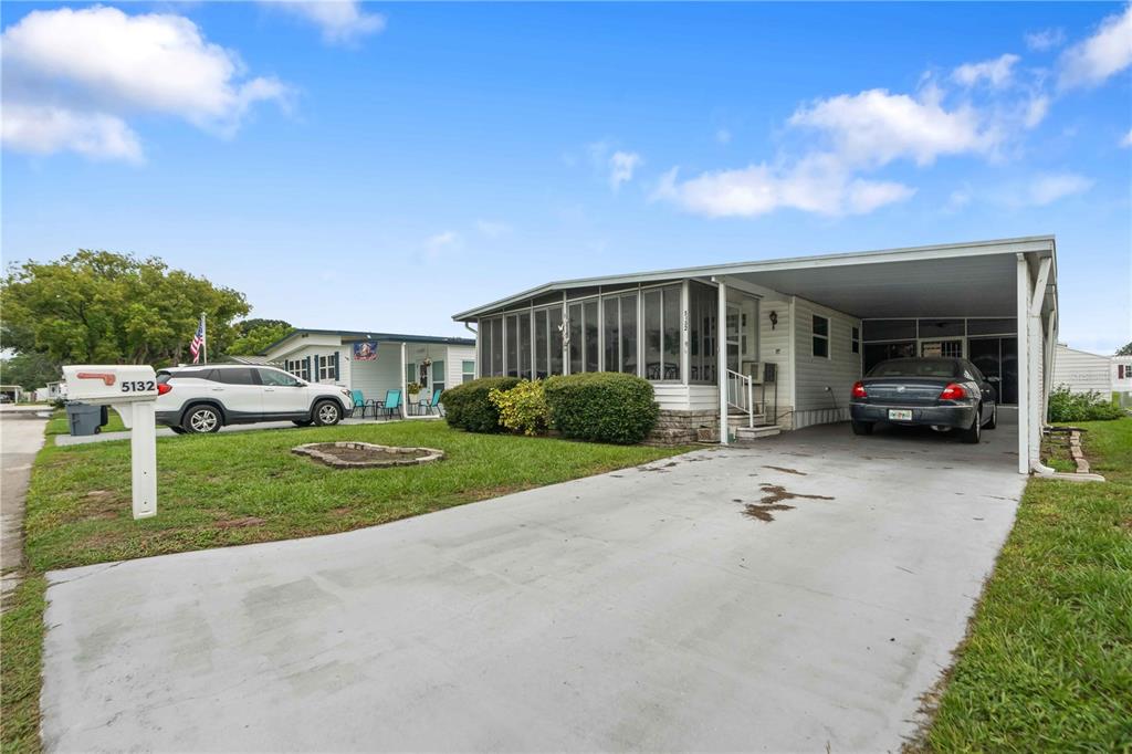 A single-story manufactured home with a screened porch, carport, and concrete driveway — 5132 BOTANY DRIVE, HOLIDAY, FL