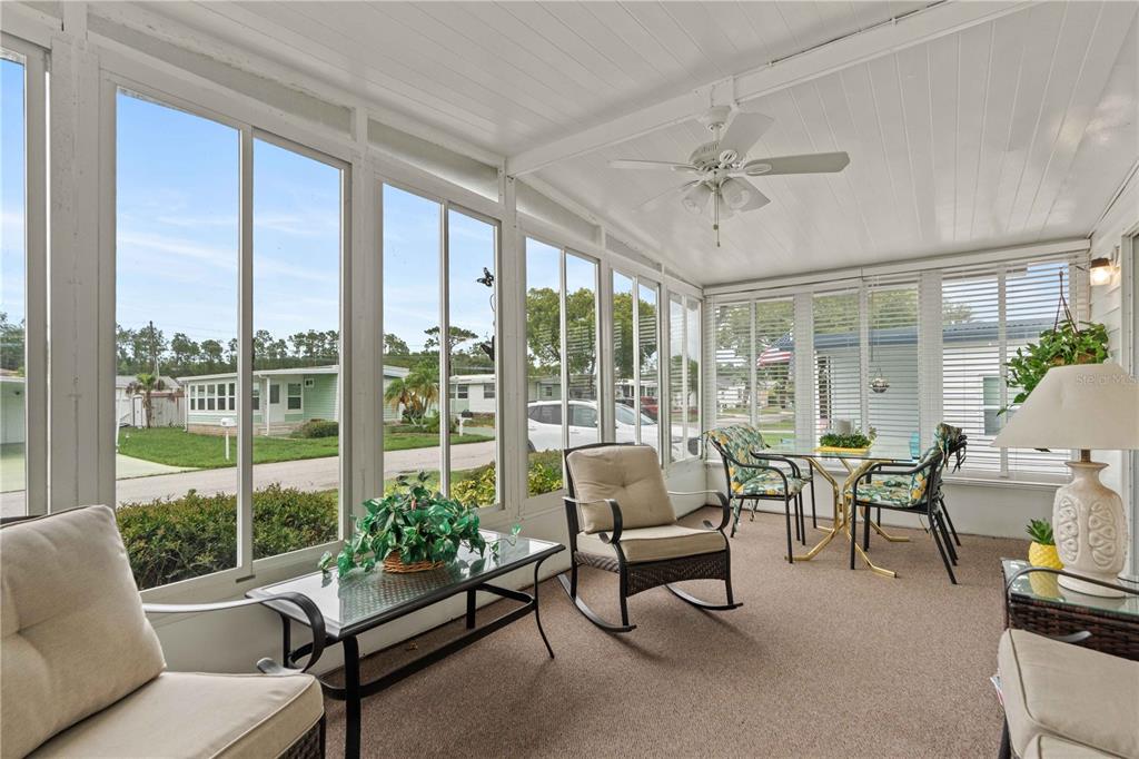 A sunroom with large windows, a ceiling fan, carpeted flooring, and patio furniture — 5132 BOTANY DRIVE, HOLIDAY, FL
