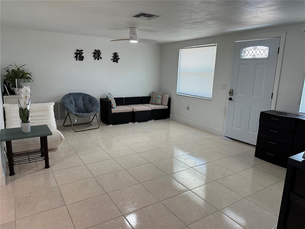 A living room features light tile flooring, white walls, a ceiling fan, and a front door — 12613 4TH ISLE, HUDSON, FL