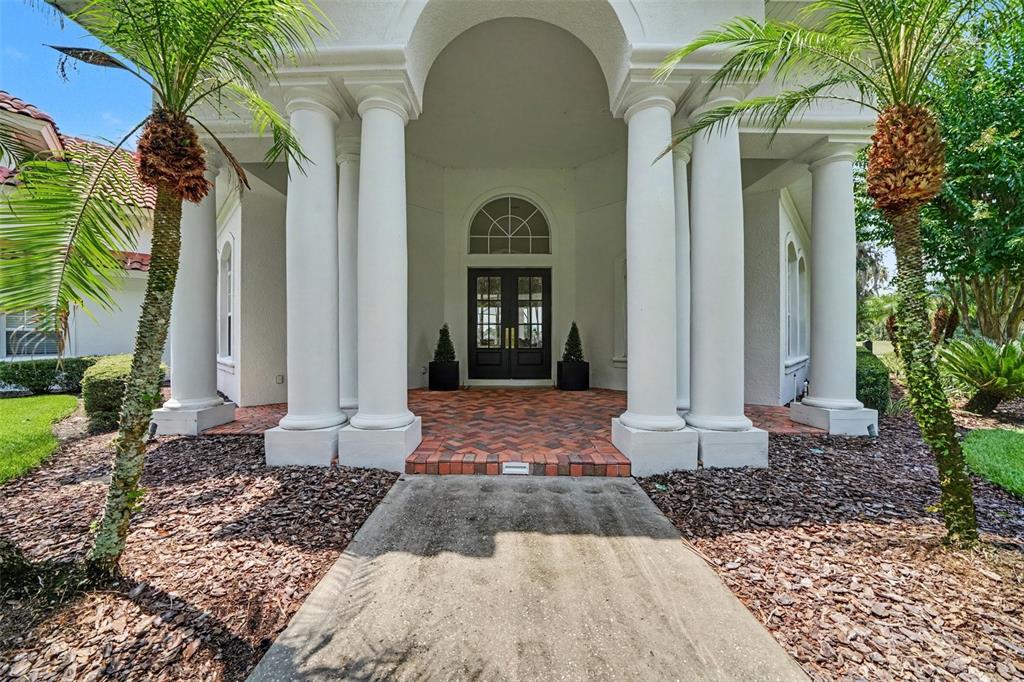 A front entrance features a brick walkway, white columns, and double doors under an archway — 3450 FOXMEADOW COURT, LONGWOOD, FL