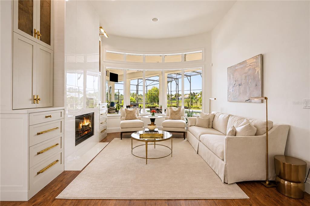 A living room features a fireplace, built-in cabinetry, a sofa, and large windows overlooking a pool — 3450 FOXMEADOW COURT, LONGWOOD, FL