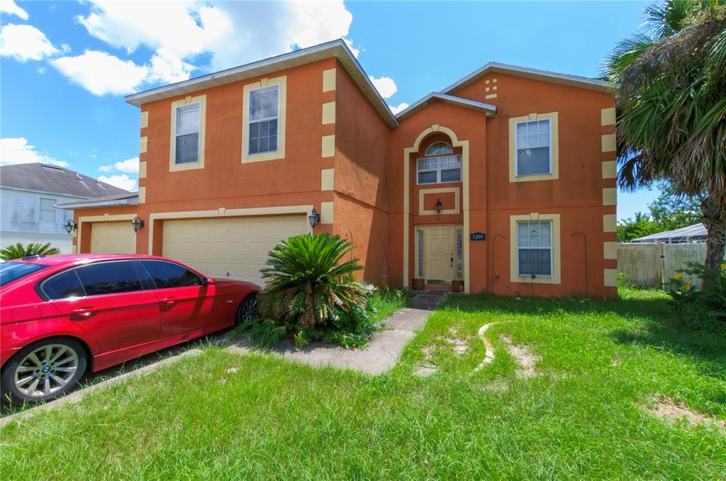 A two-story orange house with a red car parked in the driveway — 5200 SW 115TH STREET ROAD, OCALA, FL