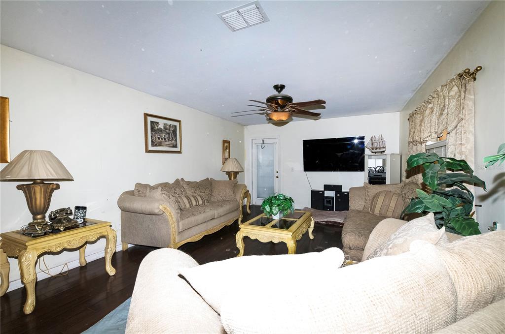 A living room features dark wood floors, beige sofas, a coffee table, and a ceiling fan — 5200 SW 115TH STREET ROAD, OCALA, FL