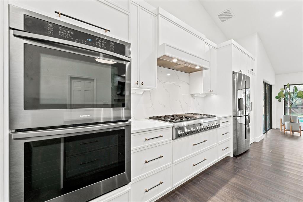 A modern kitchen features white cabinetry, stainless steel appliances, and a marble-patterned backsplash — 3969 TALAH DRIVE, PALM HARBOR, FL