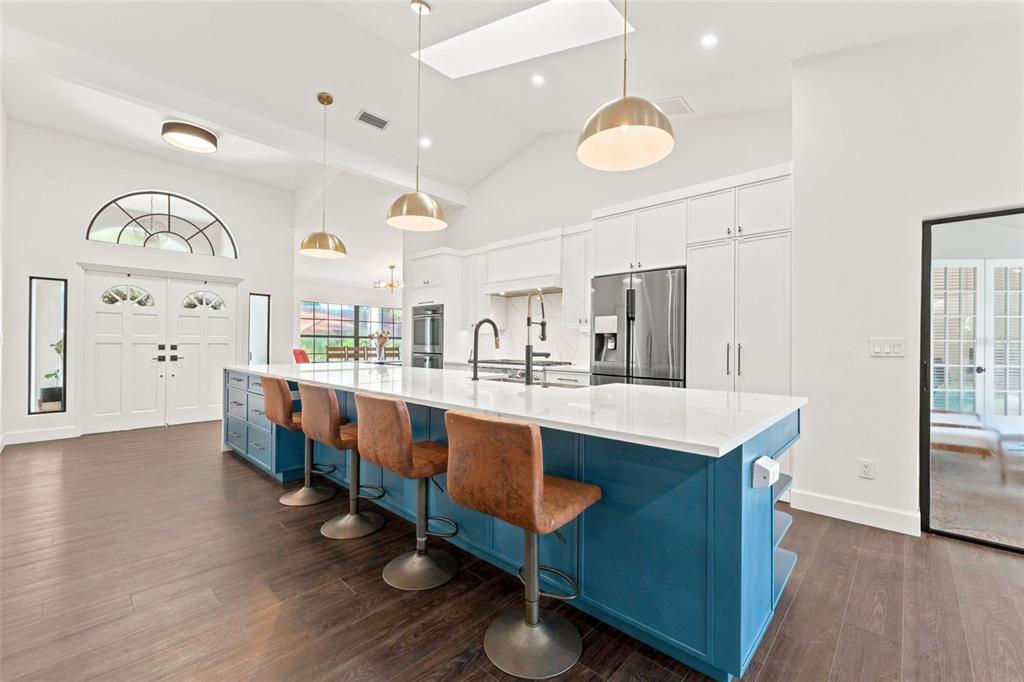A kitchen features a large blue island with bar stools, white cabinetry, and hardwood floors — 3969 TALAH DRIVE, PALM HARBOR, FL