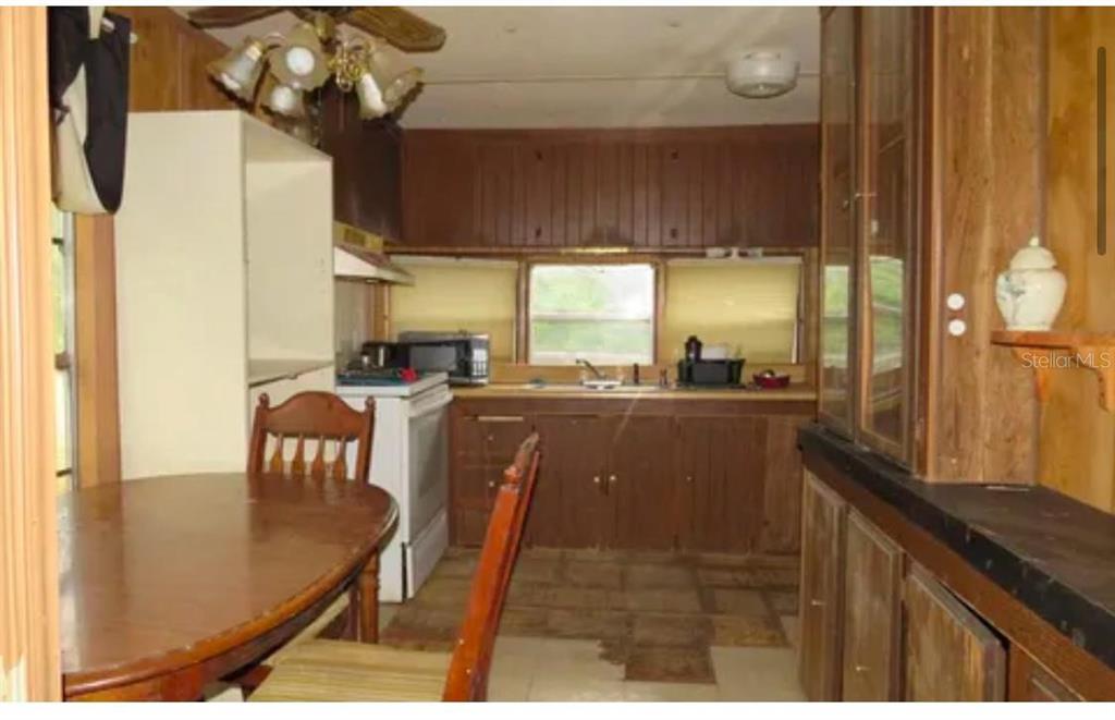 A kitchen with wood cabinets, a dining table, and a window above the sink — 10130 208TH PATH, O'BRIEN, FL