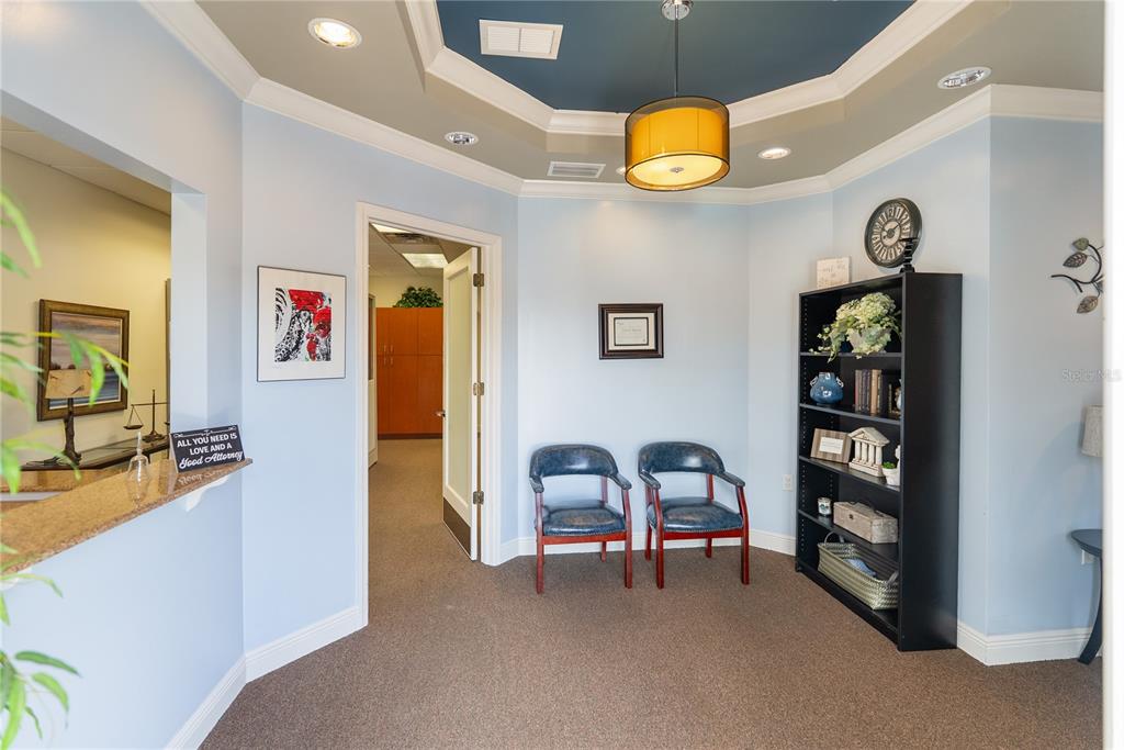 A waiting area with light blue walls, two blue chairs, a bookshelf, and a tray ceiling — 436 S TAMIAMI TRAIL UNIT C4, OSPREY, FL