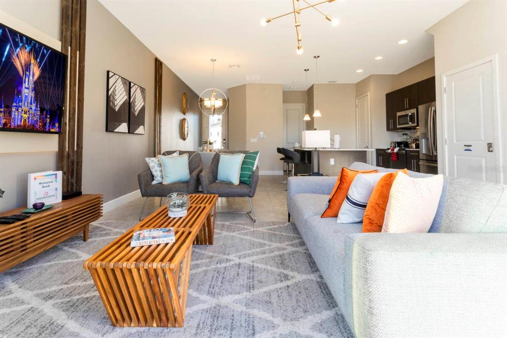 A modern living room with a gray sofa, wooden coffee table, and open kitchen area — 168 VILLA DOMANI CIRCLE, DAVENPORT, FL